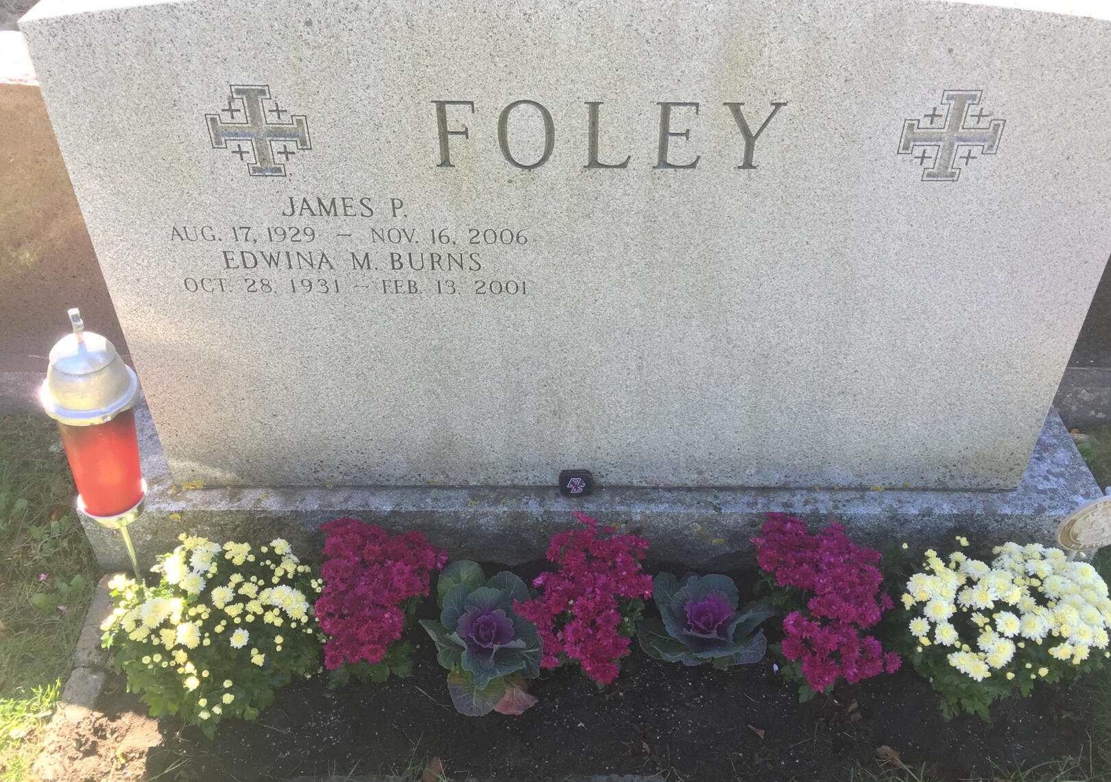A granite headstone beautifully maintained with colorful seasonal flower plantings